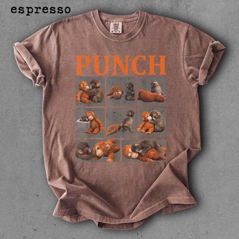 Peut inclure: T-shirt couleur expresso avec le mot "PUNCH" en lettres orange. Le t-shirt pr&eacute;sente une grille de neuf carr&eacute;s, chacun contenant une illustration diff&eacute;rente de singes. Le t-shirt est fait d'une mati&egrave;re douce et confortable.