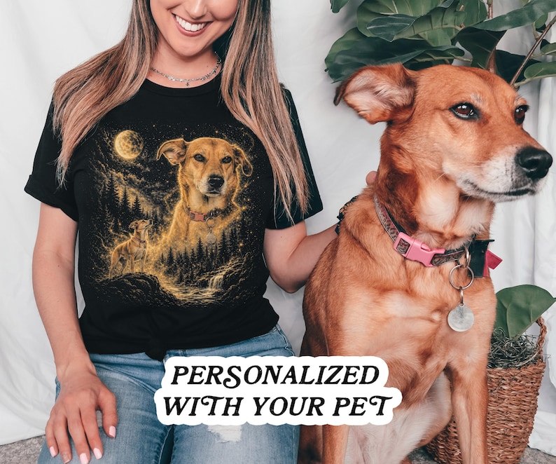 May include: A black short-sleeved t-shirt featuring a golden-toned graphic illustration of a dog in a forest setting under a full moon. The design includes a smaller dog silhouette and starry details. The text PERSONALIZED WITH YOUR PET is visible.