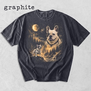 May include: A graphite-colored short-sleeve t-shirt featuring a graphic print of two French Bulldogs in a forest landscape under a full moon. The text 'graphite' is printed in the upper left corner above the shirt, which has a crew neckline.