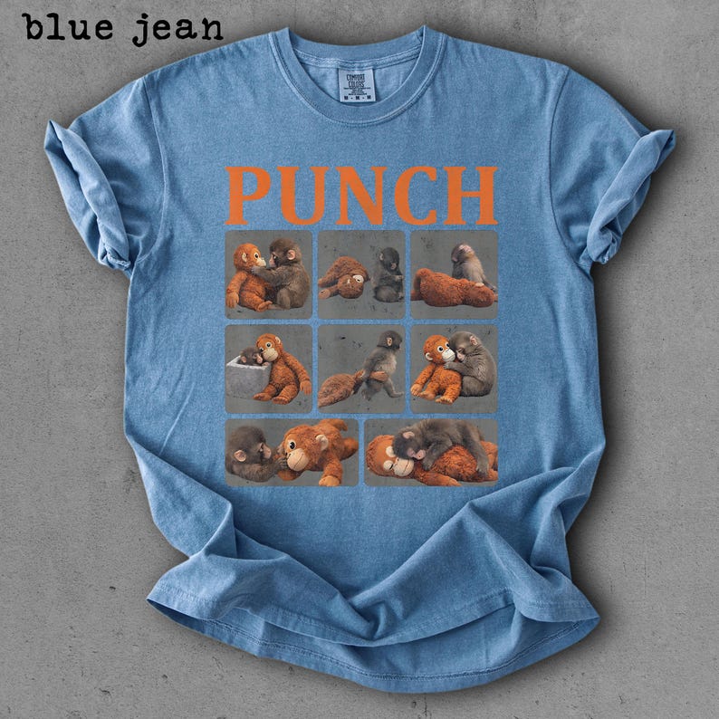 Peut inclure: T-shirt bleu jean avec le mot "PUNCH" en lettres orange. Le t-shirt pr&eacute;sente une grille de neuf carr&eacute;s, chacun avec une illustration diff&eacute;rente de singes. Le t-shirt est fait d'une mati&egrave;re douce.