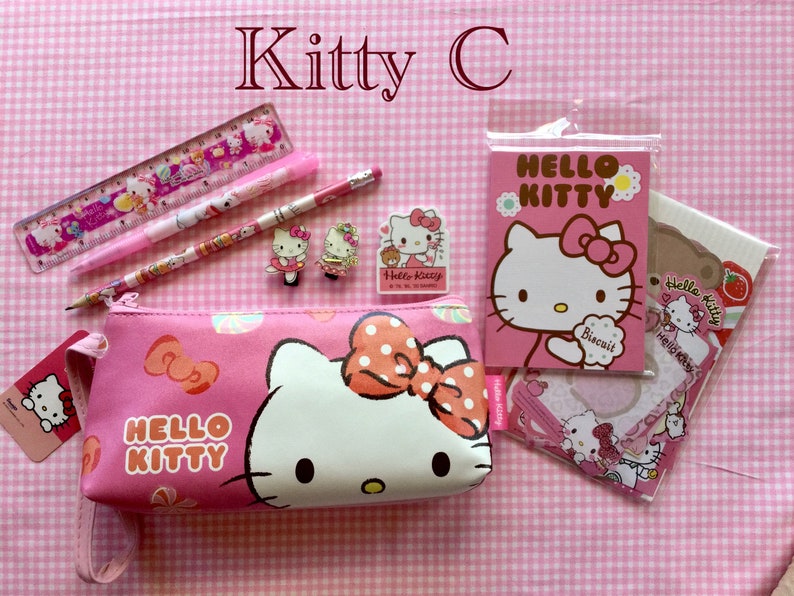 May include: Pink Hello Kitty pencil case with a zipper closure, a pink Hello Kitty ruler, a pink Hello Kitty pen, a pink Hello Kitty pencil, two Hello Kitty hair clips, and a pink Hello Kitty notepad with a Hello Kitty sticker.