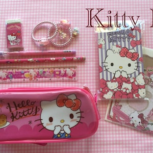 May include: Pink Hello Kitty pencil case with a Hello Kitty design, a pink ruler, two pencils, a pink eraser, and a Hello Kitty notepad and stickers.