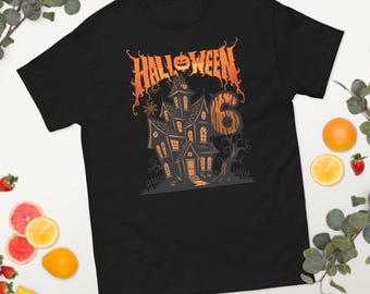 May include: Black t-shirt with a Halloween-themed graphic. The design features a haunted house, the word "Halloween" in orange, and the number "6". The graphic has a spooky, cartoonish style.