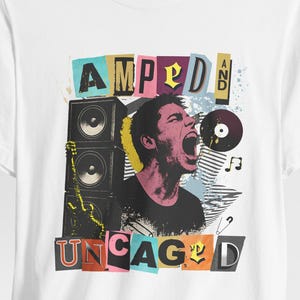 May include: White t-shirt featuring a colorful graphic design. The design includes the words "AMPED" and "UNCAGED" in a collage style, along with an illustration of a person yelling, speakers, and a vinyl record.