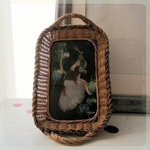May include: A woven wicker tray with a glass insert featuring a painting of a bird with blue and white feathers. The painting is set against a black background with green foliage.