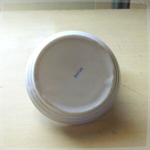 May include: White ceramic saucer with a raised rim and the word "JAPAN" printed in blue on the bottom.