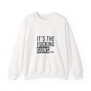 Puede incluir: Sudadera blanca de cuello redondo con el texto negro "IT'S THE FUCKING GUNS.com". La sudadera tiene mangas largas y un diseño casual.