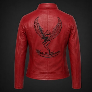 May include: A vibrant red leather jacket featuring a black graphic on the back. The design depicts a winged figure holding a rifle, positioned above the cursive text "Made In Heaven." The jacket has a classic collar, long sleeves, and seams.