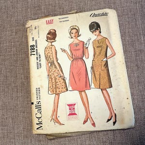 May include: Vintage McCall's sewing pattern for misses' and junior dresses. The pattern features three illustrated dress designs in various colors and patterns. The cover includes the text "Easy to Sew" and "Quickie".
