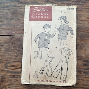 May include: A vintage sewing pattern for children's clothing. The pattern is for a two-year-old and includes a dress, a shirt, and a pair of pants. The pattern is from Fairloom Superior Patterns and is number 6293.