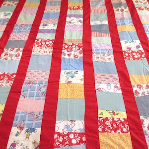 May include: A patchwork quilt with red, blue, and yellow squares. The quilt is made of different fabrics and has a vintage look.