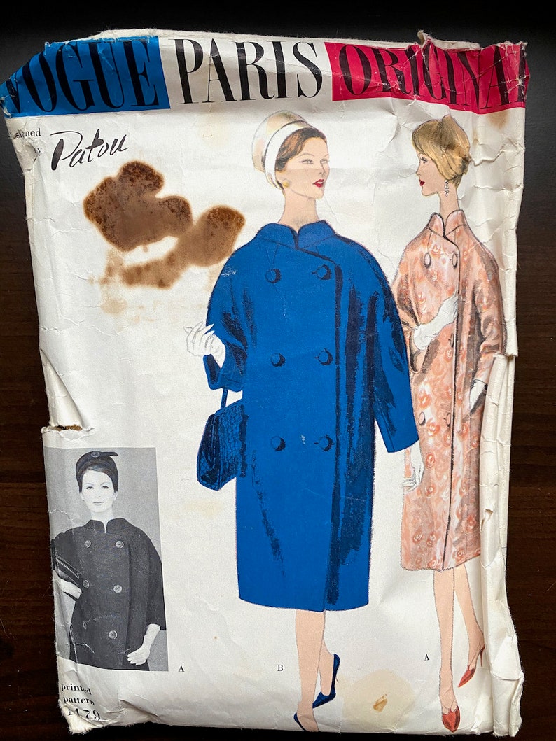 Pode incluir: Padr&atilde;o de costura vintage Vogue Paris Original desenhado por Patou. O padr&atilde;o apresenta duas mulheres vestindo casacos. Um casaco &eacute; azul e o outro &eacute; estampado floral. O padr&atilde;o &eacute; impresso em papel branco com texto preto.