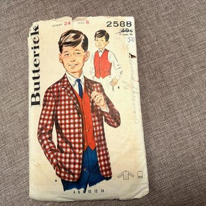 May include: Vintage Butterick sewing pattern for a boy's suit, featuring a red and white plaid jacket, red vest, and blue pants. The pattern number is 2588, with a chest size of 24 inches and size 6. The price is 40 cents.