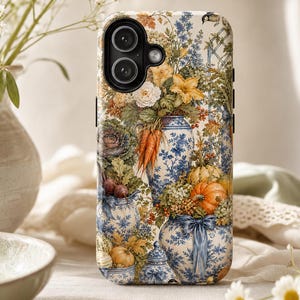 May include: A rectangular smartphone case featuring a detailed print of blue and white ceramic vases filled with orange carrots, pumpkins, and various garden flowers. The design includes lush greenery and autumn-toned foliage against a cream background.