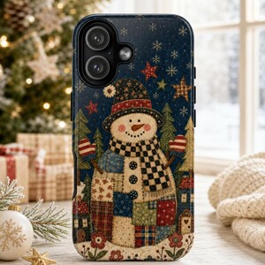 Op de afbeelding: Een donkerblauw smartphonehoesje met een illustratie van een sneeuwpop in patchworkstijl. De sneeuwpop draagt een hoed en sjaal, omringd door kleine huisjes, groenblijvende bomen, sterren en sneeuwvlokken met diverse kleurrijke patronen.