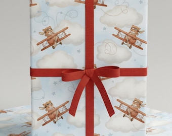 May include: Gift-wrapped present with light blue wrapping paper featuring a repeating pattern of cartoon bears in biplanes, clouds, and stars. A red ribbon and bow secure the gift. The overall theme is a children's gift.