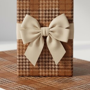 May include: A wrapped gift box with a brown and cream houndstooth pattern. A cream-colored bow is tied around the box with a matching ribbon. The box is sitting on a matching patterned surface.