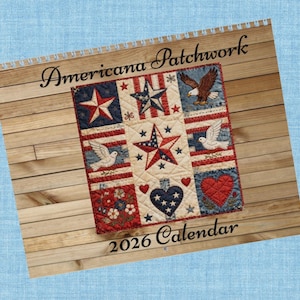 May include: A 2026 calendar with an Americana patchwork design. The calendar features a quilt-like pattern with stars, an eagle, doves, and hearts in red, white, and blue. The words "Americana Patchwork" and "2026 Calendar" are displayed.