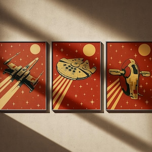 Peut inclure: Ensemble de trois impressions d'art encadrées représentant des vaisseaux spatiaux emblématiques sur un fond rouge avec un soleil jaune et des étoiles. Les impressions présentent un chasseur stellaire, le Faucon Millenium et Slave I.