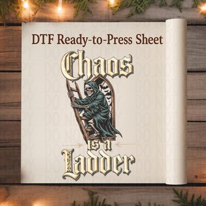 May include: DTF ready-to-press sheet featuring a grim reaper climbing a ladder, with the words "Chaos is a Ladder". The design is in shades of green, beige, and brown, with a gothic font. The sheet is rolled up, ready for use.