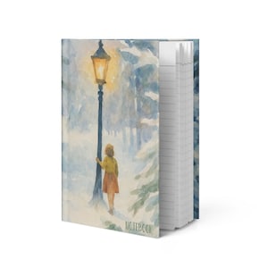 May include: A notebook featuring a watercolour illustration of a person standing by a glowing street lamp in a snowy forest. The cover displays the word NOTEBOOK at the bottom. The side shows white lined pages bound within the hard cover.