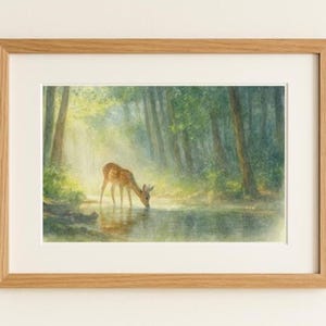 Könnte beinhalten: Ein gerahmter Aquarelldruck zeigt ein junges Reh, das in einem sonnendurchfluteten Wald aus einem Bach trinkt. Das Kunstwerk hat einen hellbraunen Holzrahmen und ein weißes Passepartout, das die sanften Farben der Szene hervorhebt.