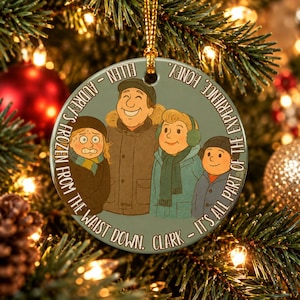 Può includere: Una decorazione natalizia rotonda in ceramica con un'illustrazione di quattro persone in cappotti invernali. Il testo recita: ELLEN - AUDREY'S FROZEN FROM THE WAIST DOWN. CLARK - IT'S ALL PART OF THE EXPERIENCE, HONEY.