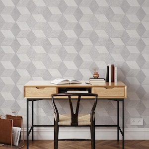 Puede incluir: Una configuración de oficina en casa con un escritorio de madera con marco de metal negro, una silla de madera y un papel pintado con patrones geométricos en tonos grises. El escritorio contiene libros, un jarrón y un revistero.