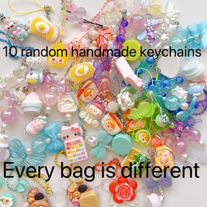 May include: A collection of 10 random handmade keychains featuring colorful plastic charms, beads, and miniature figures in various shapes like butterflies, food, and characters. The text 10 random handmade keychains and Every bag is different is visible.