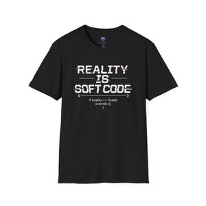 Könnte beinhalten: Schwarzes T-Shirt mit dem weißen Text "REALITY IS SOFT CODE" mit einem Glitch-Effekt. Unter dem Text befindet sich eine Codezeile: "if (reality == fixed){ override (); }."