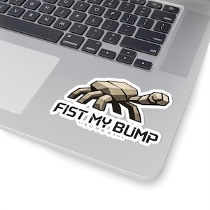 Puede incluir: Una pegatina blanca con el texto "FIST MY BUMP" y un diseño geométrico de cangrejo. La pegatina está sobre un portátil. El cangrejo es beige y negro.