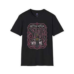 May include: Black t-shirt featuring a decorative design with the words "DON'T PLAY WITH ME" and "STAY WITH ME" in a stylized font. The design includes a sword and ornate pink and white accents.