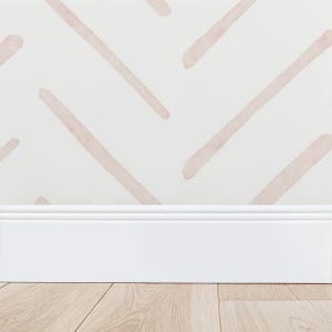 May include: A close-up of a wall with a white background and a pattern of diagonal, blush-colored brushstrokes. A white baseboard runs along the bottom, with a light wood floor in the foreground. The design is simple and modern.