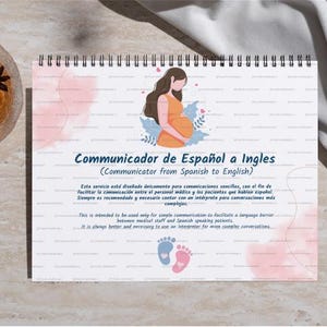 May include: A spiral-bound notepad with the title "Communicator from Spanish to English" and an illustration of a pregnant person. The notepad is on a light-colored surface, next to a glass of tea.