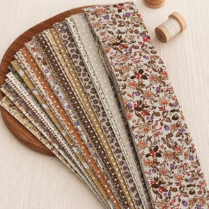May include: A collection of long, narrow fabric strips arranged in a fan shape. The strips feature various patterns including floral prints with red and purple flowers, brown leopard spots, white polka dots, and small stars on beige and brown backgrounds.