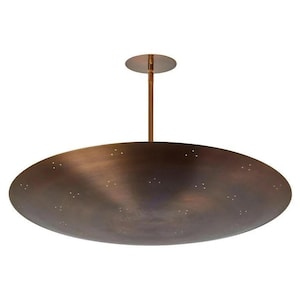 May include: A bronze-colored, oval-shaped ceiling light fixture. The fixture has a flat, disc-shaped shade with small, evenly spaced holes. It is suspended from the ceiling by a brass-colored rod and a circular ceiling plate. The overall design is minimalist and modern.