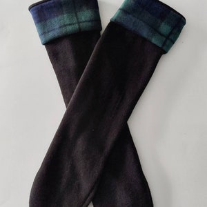 May include: A pair of black knee-high socks with a blue and green tartan cuff. The socks are made from a soft fabric and are designed to be worn over the calf. The tartan cuff adds a classic touch to the design.