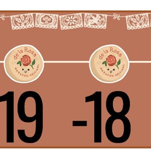 May include: A brown rectangular paper strip featuring a row of white papel picado banners at the top, four circular de la Rosa mazapán logos, and the black numbers -20, -19, -18, and -17. The right side includes a white vertical tab labeled Glue here.
