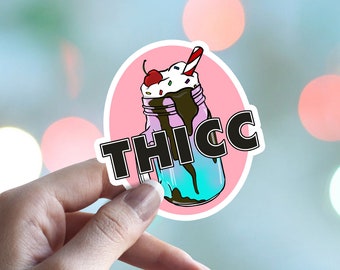 May include: Pink and blue sticker with a cartoon illustration of a milkshake with a cherry on top and the word "THICC" in black letters.