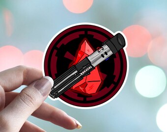 May include: A red and black sticker with a lightsaber and the symbol of the Galactic Empire. The lightsaber is partially obscured by the symbol.