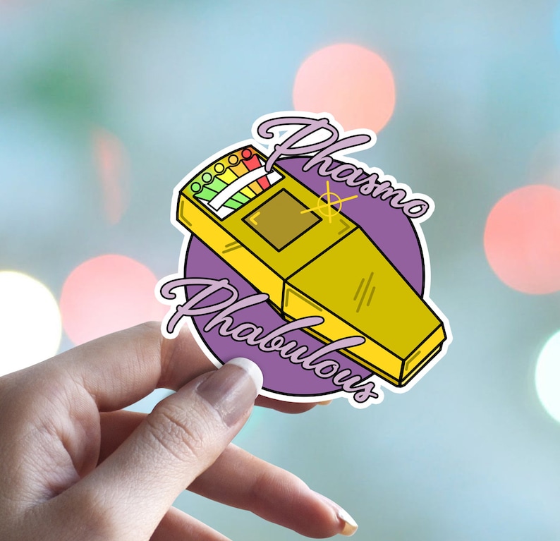 May include: A purple and white sticker with a cartoon illustration of a yellow ghost hunting meter. The meter has a rainbow colored gauge and the text "Phasmo Fabulous" is written around the meter.