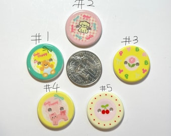 May include: A collection of five decorative buttons with cartoon puppy and floral designs. The buttons are in various colors, including pink, yellow, and green. The buttons are round and have two or four holes for sewing. A US quarter is included for size comparison.