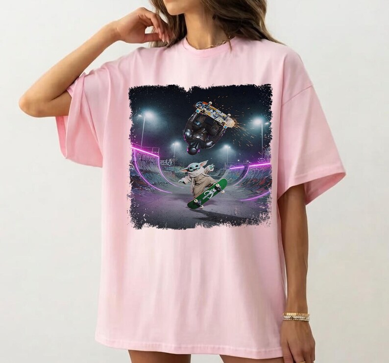 K&ouml;nnte beinhalten: Hellrosa T-Shirt mit einem Aufdruck eines Charakters, der in einem Skatepark skateboardet. Der Aufdruck zeigt ein gr&uuml;nes Skateboard, eine Figur und einen schwarzen Skateboarder. Der Hintergrund zeigt einen Skatepark mit neonvioletten Lichtern.