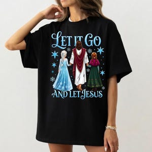May include: Black t-shirt with the text "Let It Go and Let Jesus" in blue script. The graphic features three figures: Jesus, and two characters in blue and green dresses. Snowflakes are scattered around the figures.