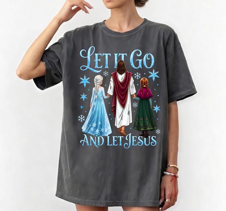 May include: Dark gray t-shirt featuring the text "Let It Go AND LET JESUS" in blue script. The graphic includes illustrations of Jesus and two characters from the movie Frozen, with snowflakes. The shirt is a casual, oversized style.