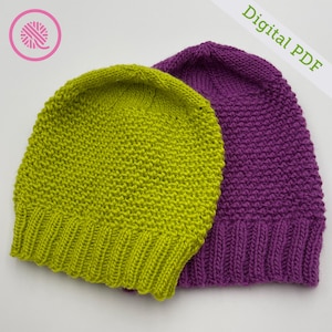 Puede incluir: Dos gorros de punto, uno verde y otro morado, con un patrón de punto texturizado. Los gorros están doblados y apilados uno encima del otro. PDF digital.