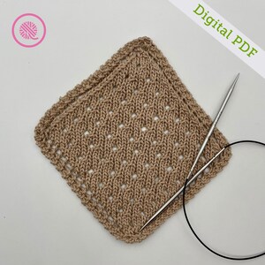 May include: A close-up of a beige knitted square with a lacy pattern. Two knitting needles and a black circular needle are lying on top of the square. The text "Digital PDF" is written in green letters on a white background.