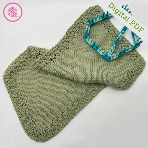May include: A green knitted dishcloth with a decorative border. The dishcloth is folded and lying on a white surface. A plastic knitting loom is also visible in the image. The text "Digital PDF" is written on a white label.