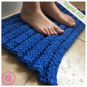 May include: A close-up of a blue knitted bath mat with a person's feet standing on it. The mat is made of thick, woven yarn and has a textured surface. The text "Digital PDF" is visible in the upper right corner of the image.