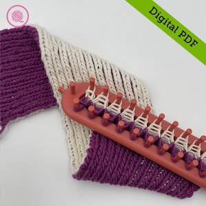 May include: A close-up of a knitting loom with a purple and white knitted fabric on it. The loom is pink and has a row of pegs. The fabric is partially knitted and partially on the loom. The text "Digital PDF" is visible in the upper right corner of the image.